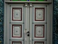 Haustür in grau mit Ausschnitten in rot und Verzierung 
