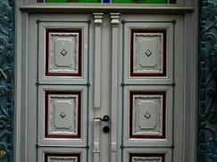 Haustür in grau mit Ausschnitten in rot und Verzierung