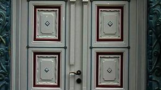Haustür in grau mit Ausschnitten in rot und Verzierung 