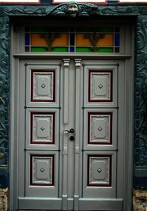 Haustür in grau mit Ausschnitten in rot und Verzierung 